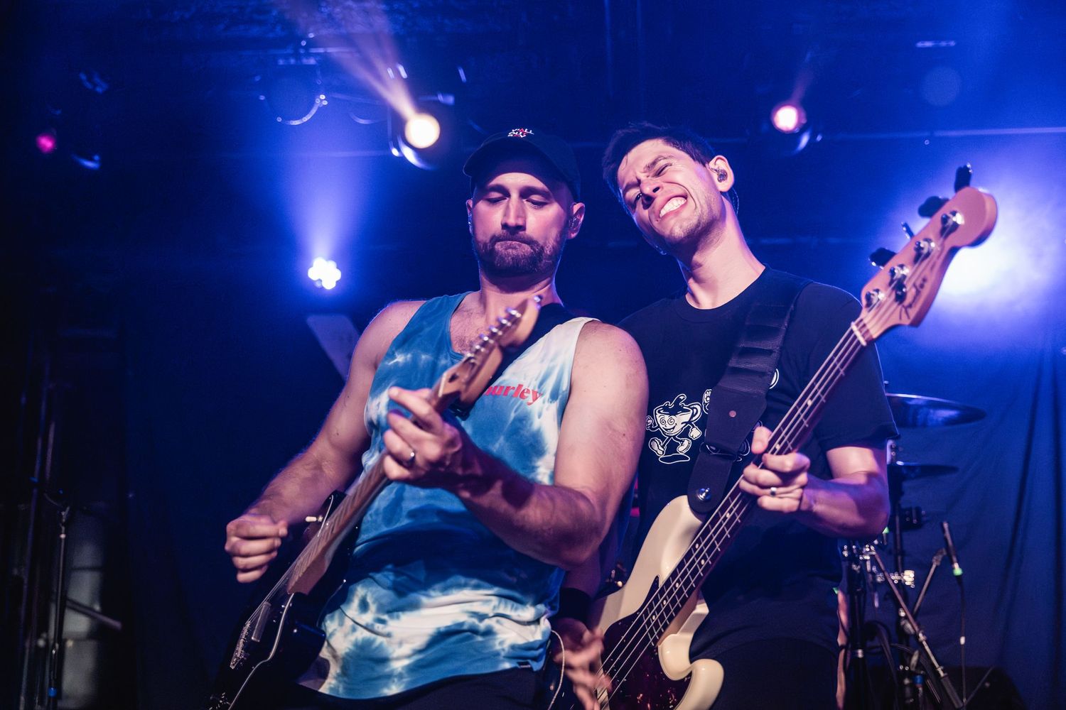Musicians performing together on stage with vibrant blue lighting effects.