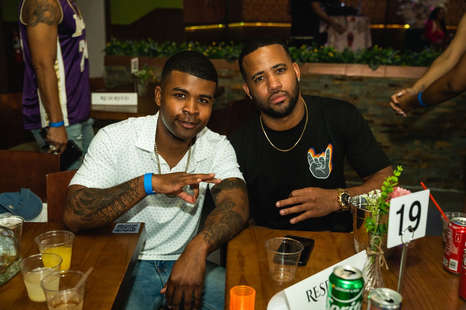 Two friends enjoying drinks and conversation at outdoor table with numbered centerpiece.