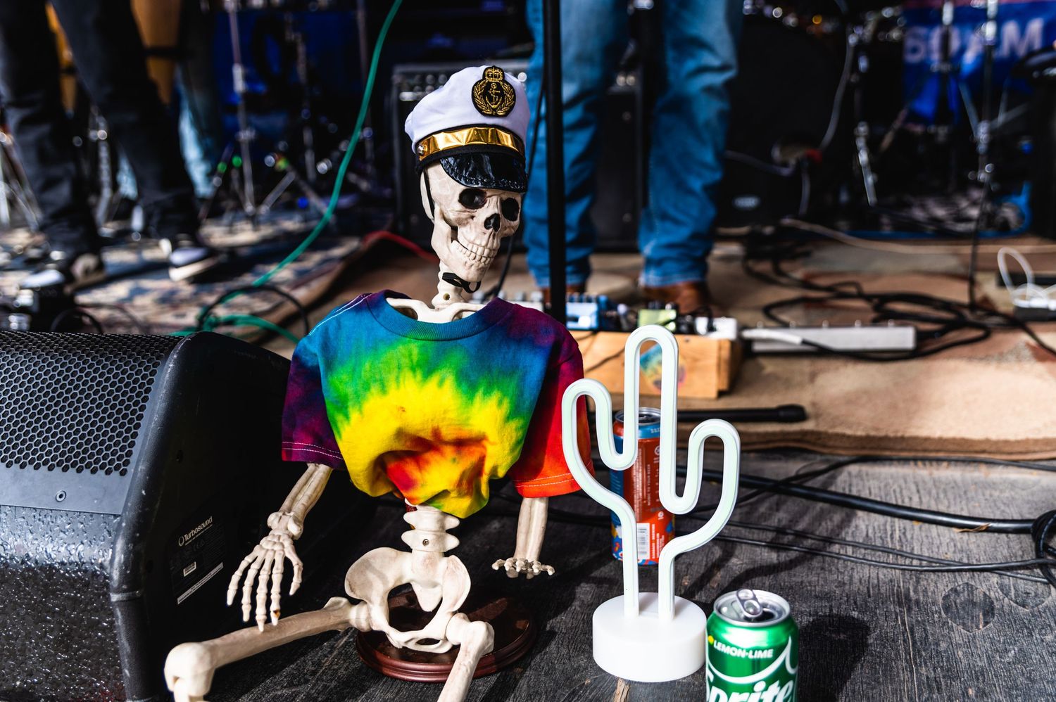 Decorative skeleton wearing tie-dye shirt and captain hat displayed near stage equipment.
