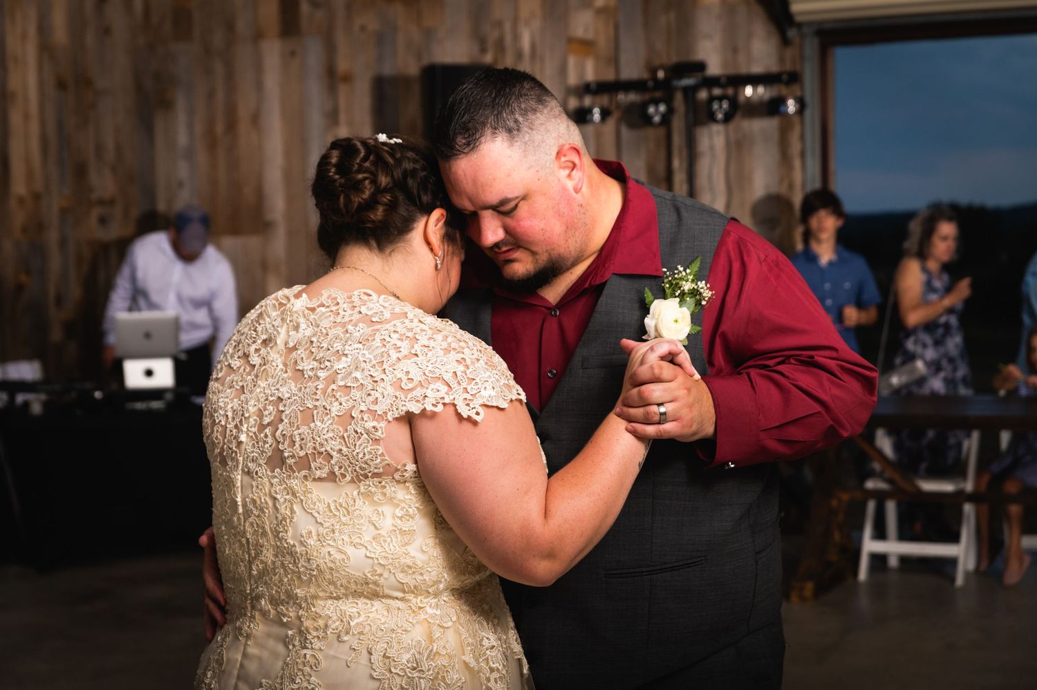 A couple dances together in an intimate moment at their wedding reception in a rustic venue.