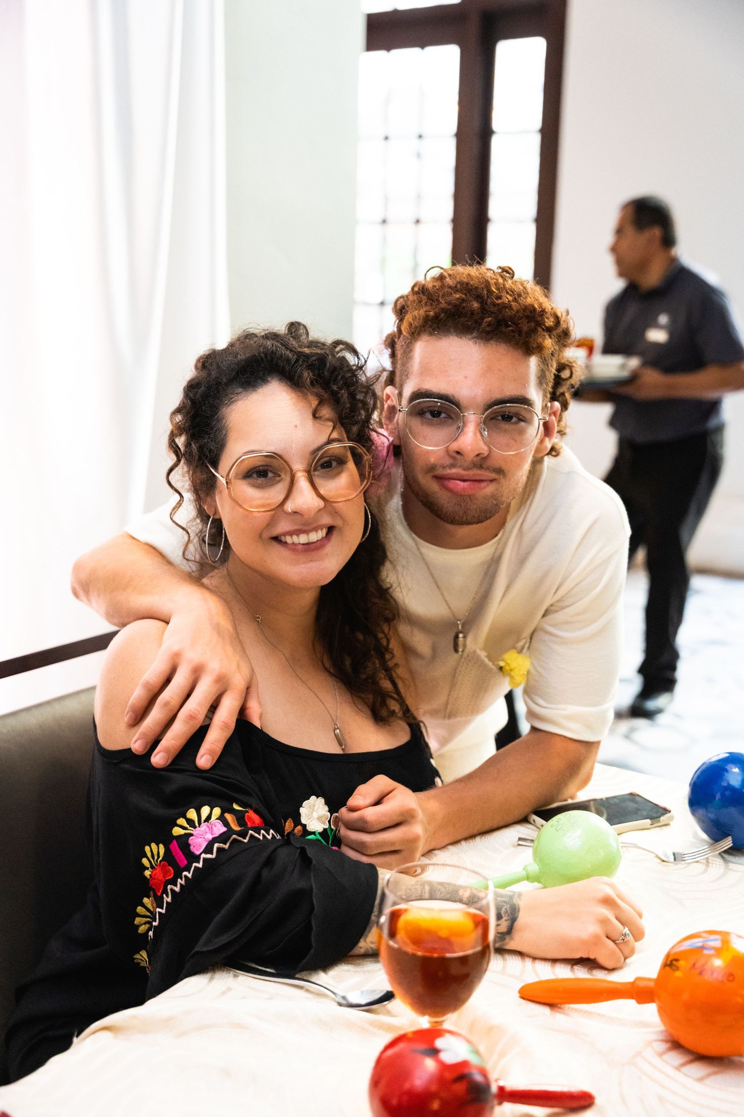 Young couple shares intimate moment at reception table with colorful party decorations.