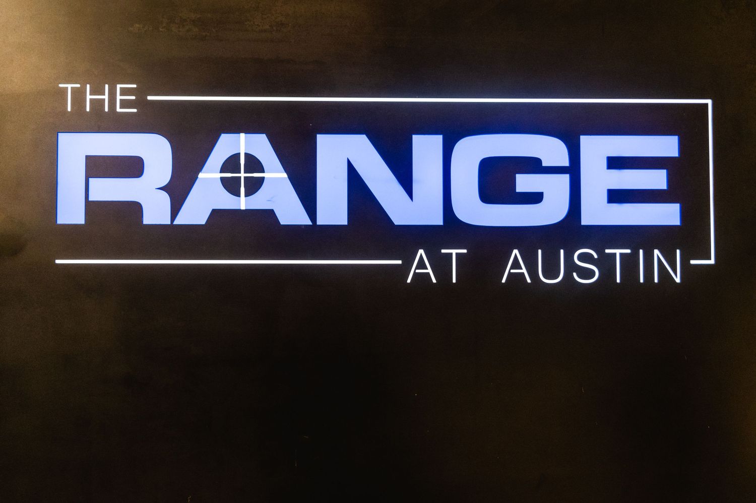 Illuminated logo sign reading 'THE RANGE AT AUSTIN' with crosshair design.