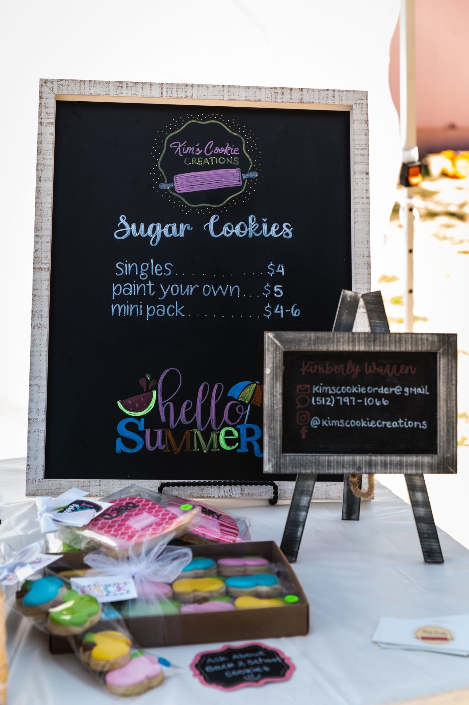A chalkboard menu displays sugar cookie prices and summer-themed text with decorative lettering.
