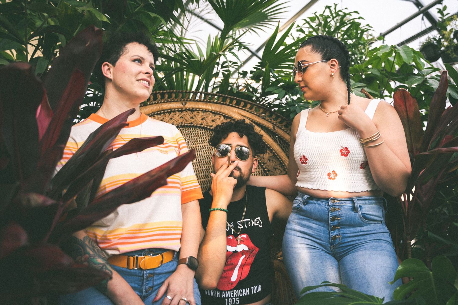 Friends enjoying a casual moment together in a greenhouse or garden setting.