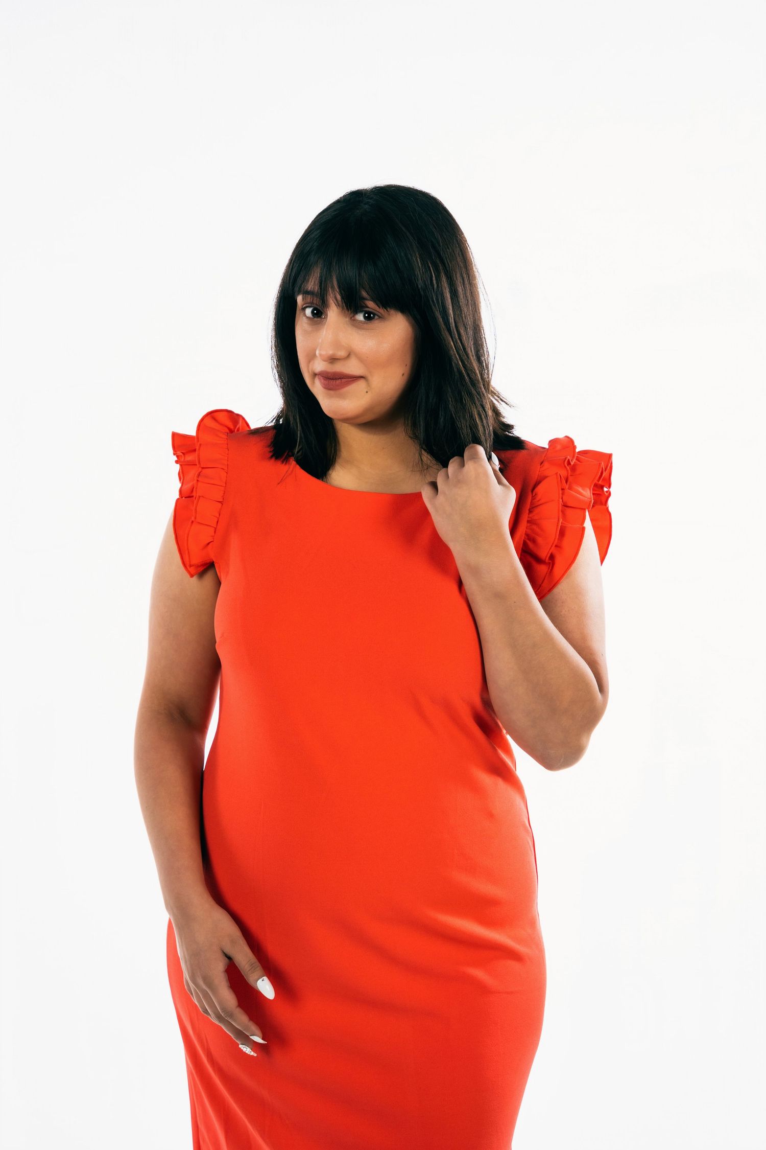 Woman in a bright red ruffle sleeve dress posing against a white backdrop.