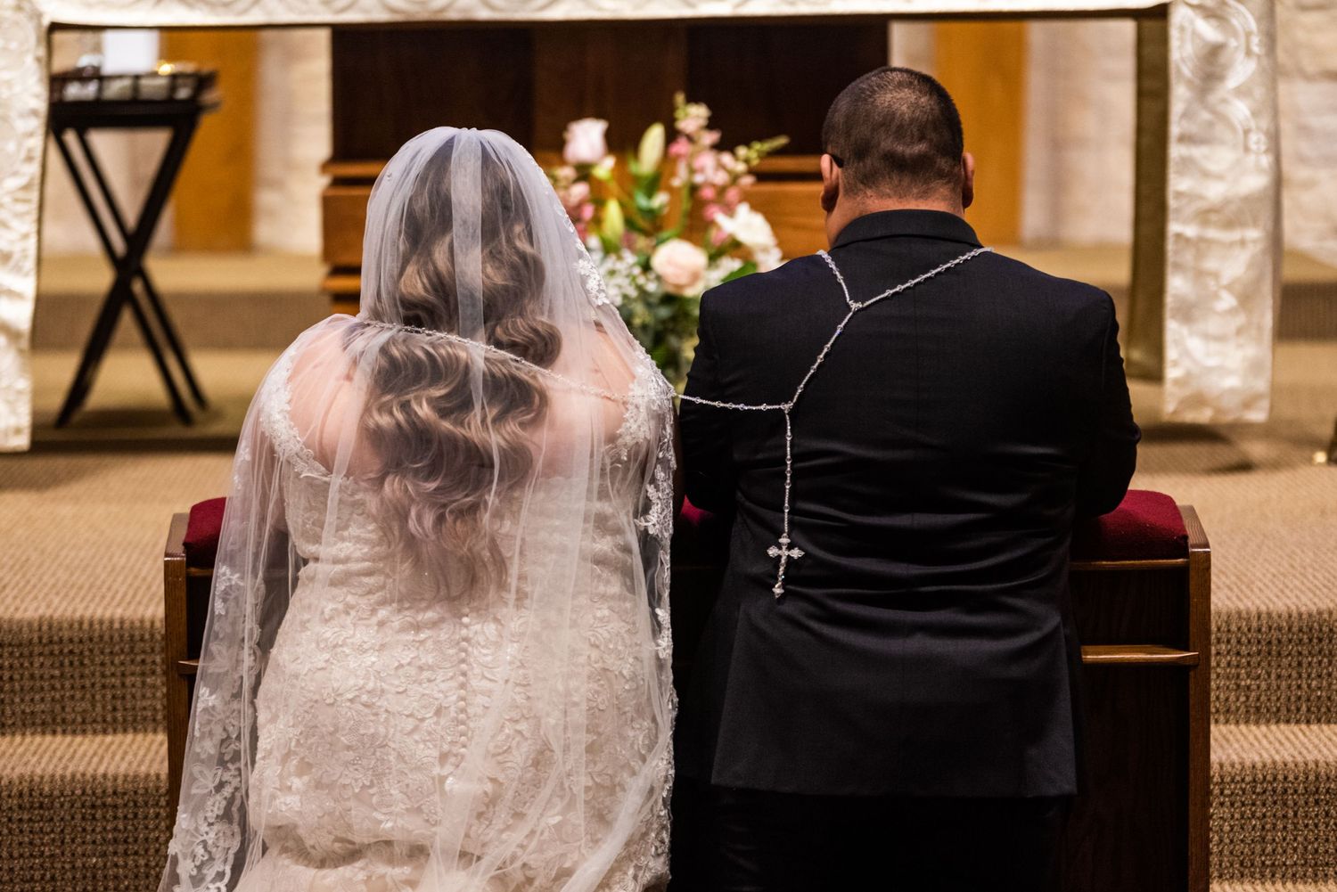 A couple kneels before the altar during their Catholic wedding ceremony.
