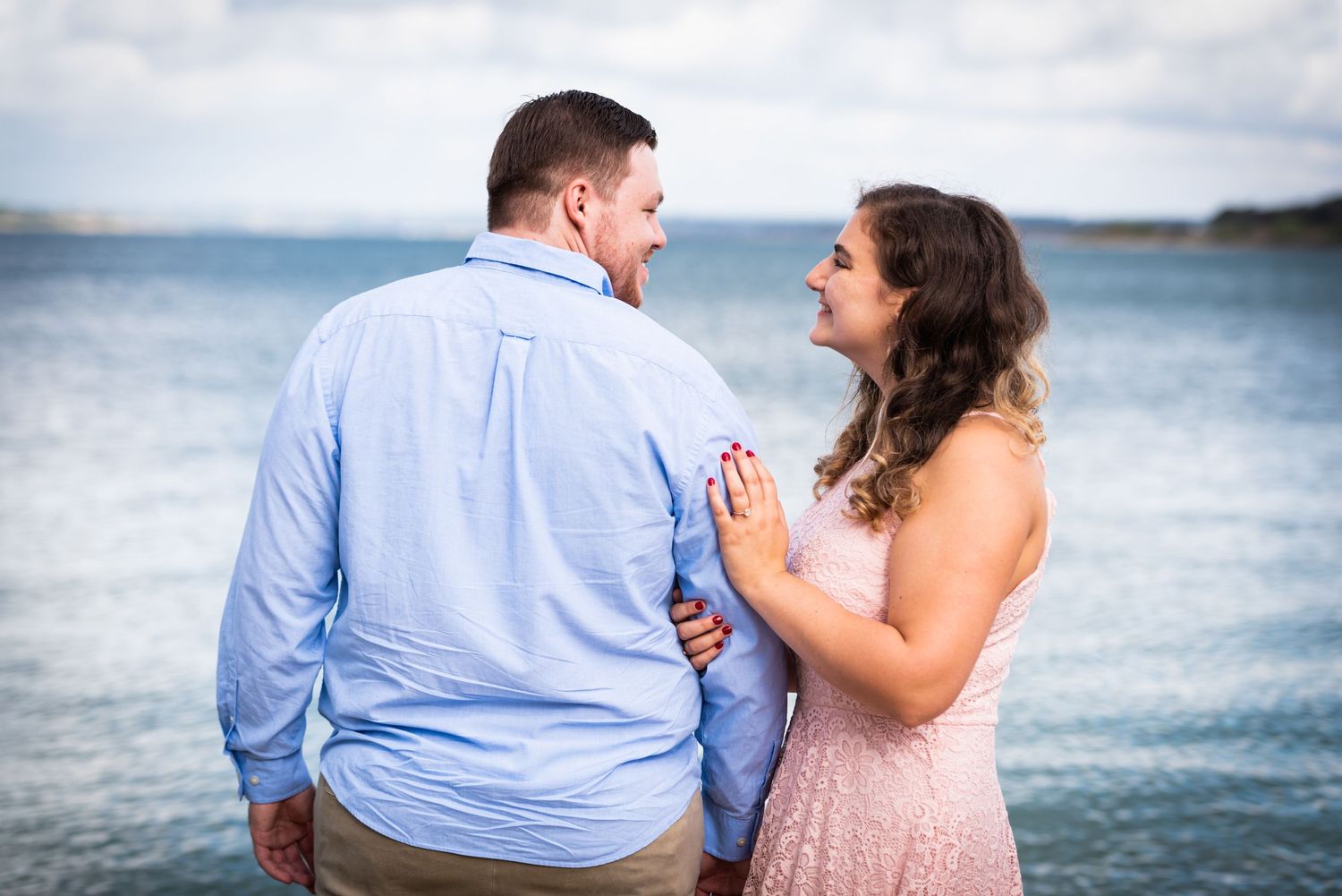 A couple shares an emotional moment against a serene ocean backdrop.