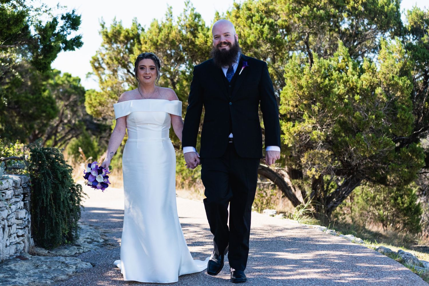 A couple walks together on a stone path during their wedding day.