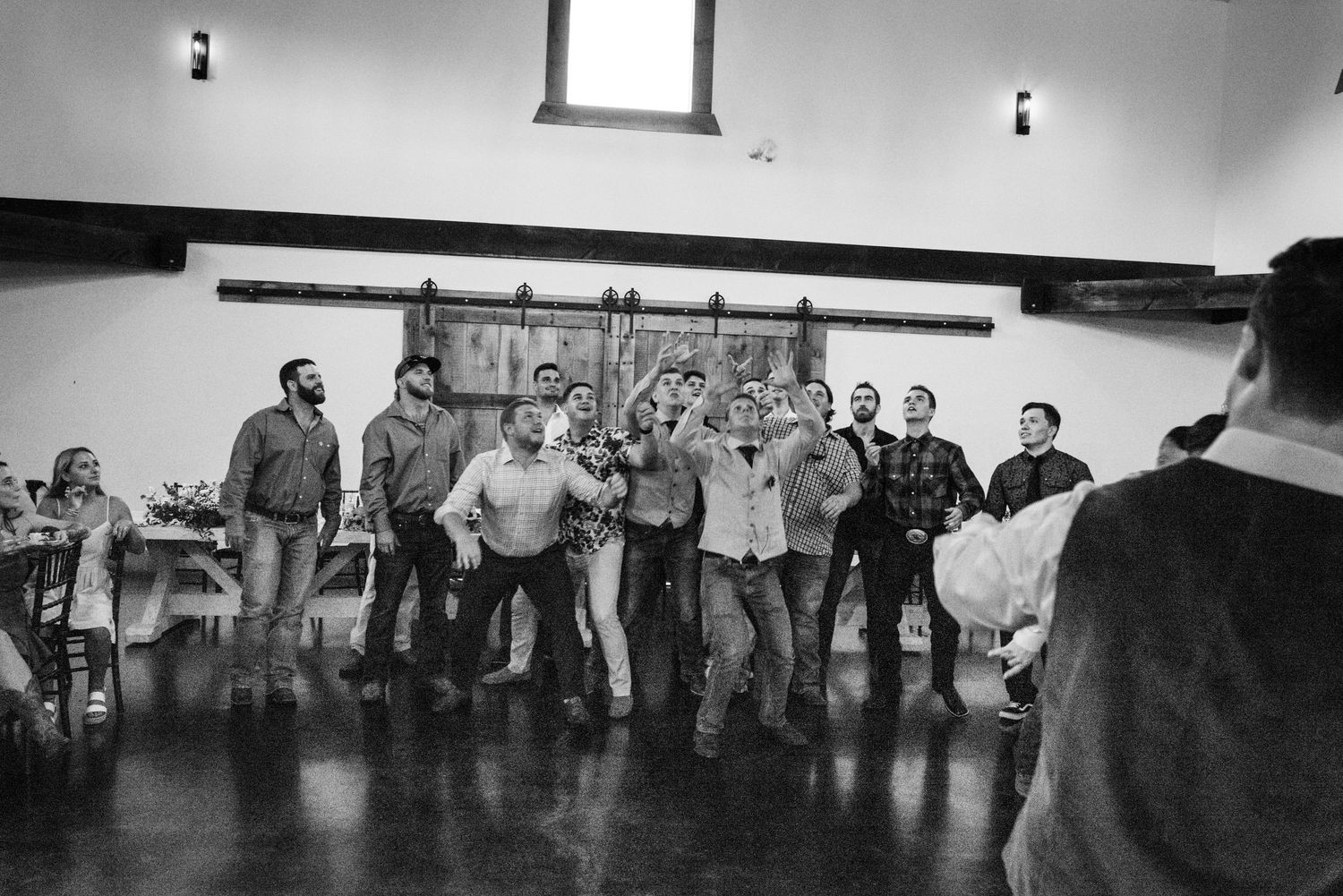Black and white photo of wedding guests lined up for group dance at reception.