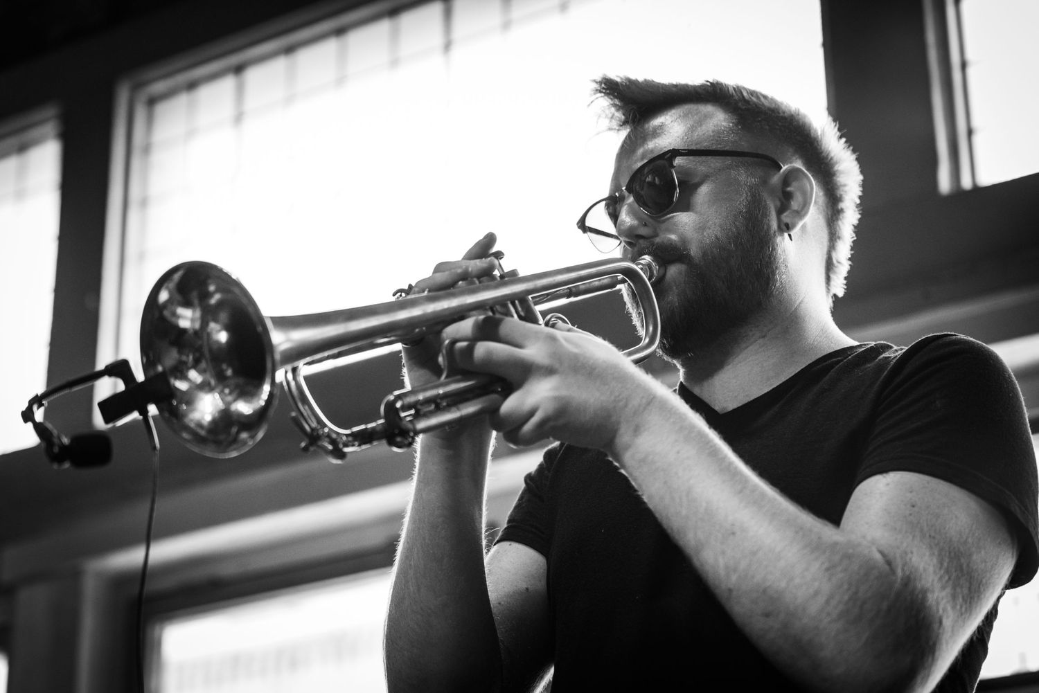 Black and white close-up shot of trumpet player performing with intense focus.
