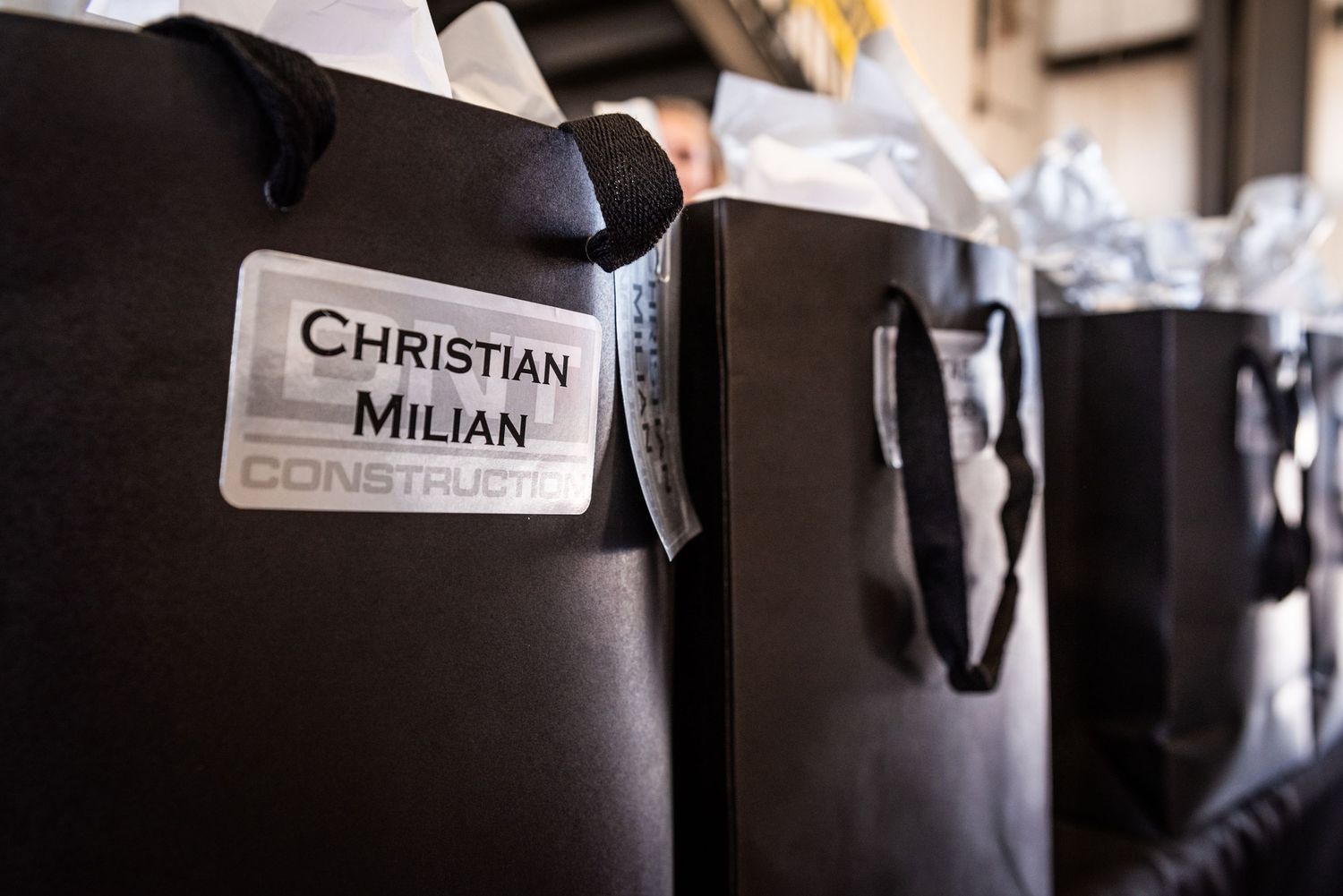 Close-up of designer shopping bags with Christian Milian branding lined up at an event.