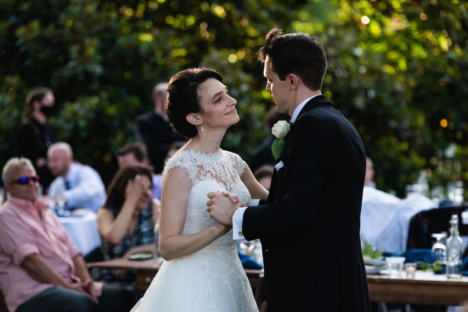Couple shares an intimate dance moment during their outdoor wedding reception at sunset.