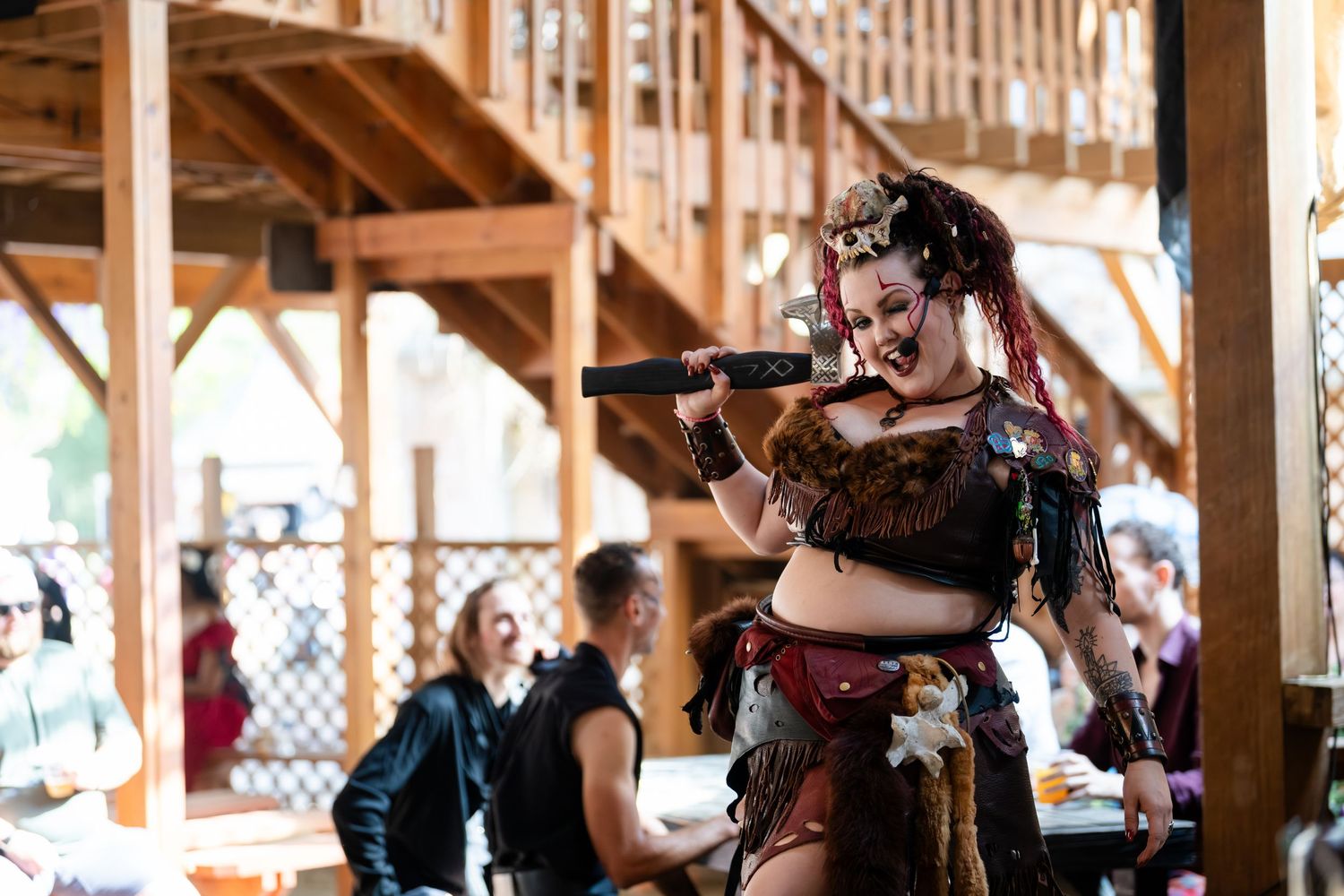 Musicians perform on string instruments during a traditional folk music concert under a wooden pavilion structure.