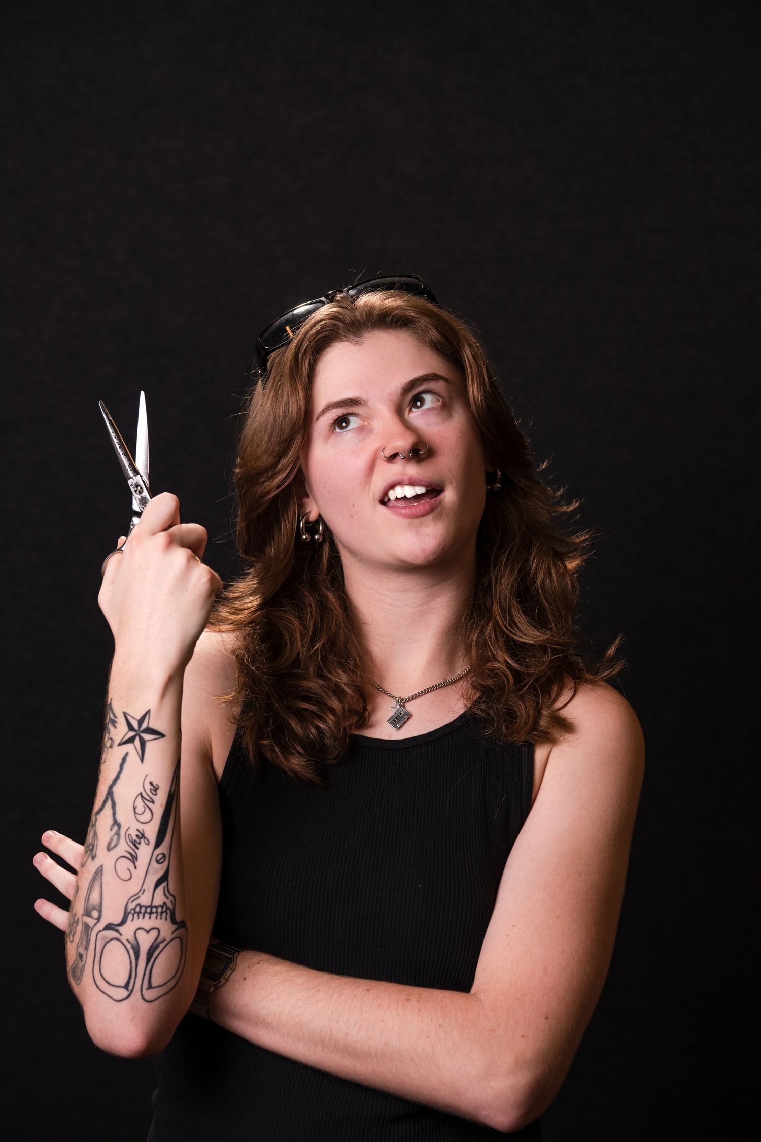 A person in black clothing poses with scissors against a dark background in a creative portrait series.