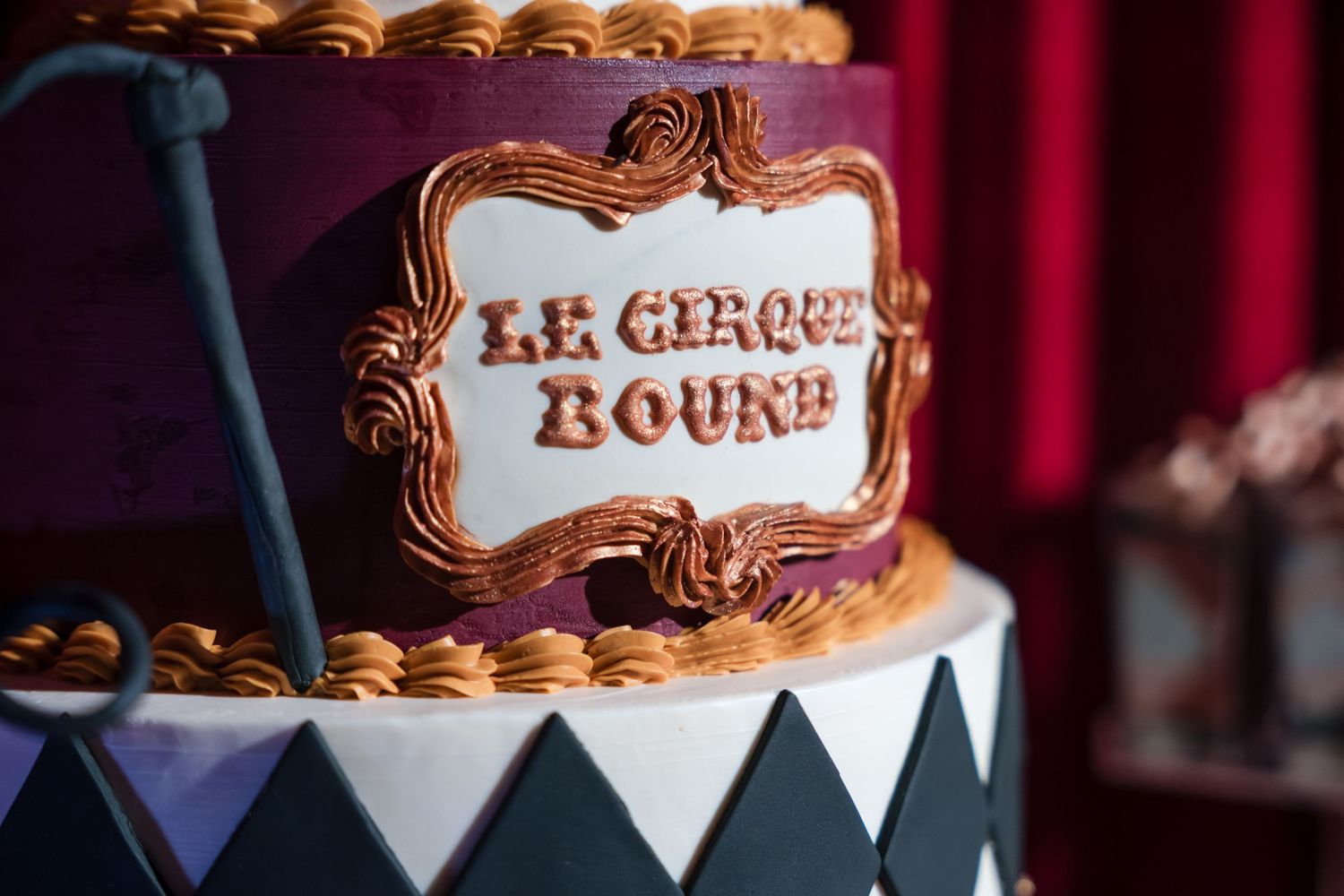 A chocolate brown wedding cake decorated with ornate copper details and white triangular bunting around the base.