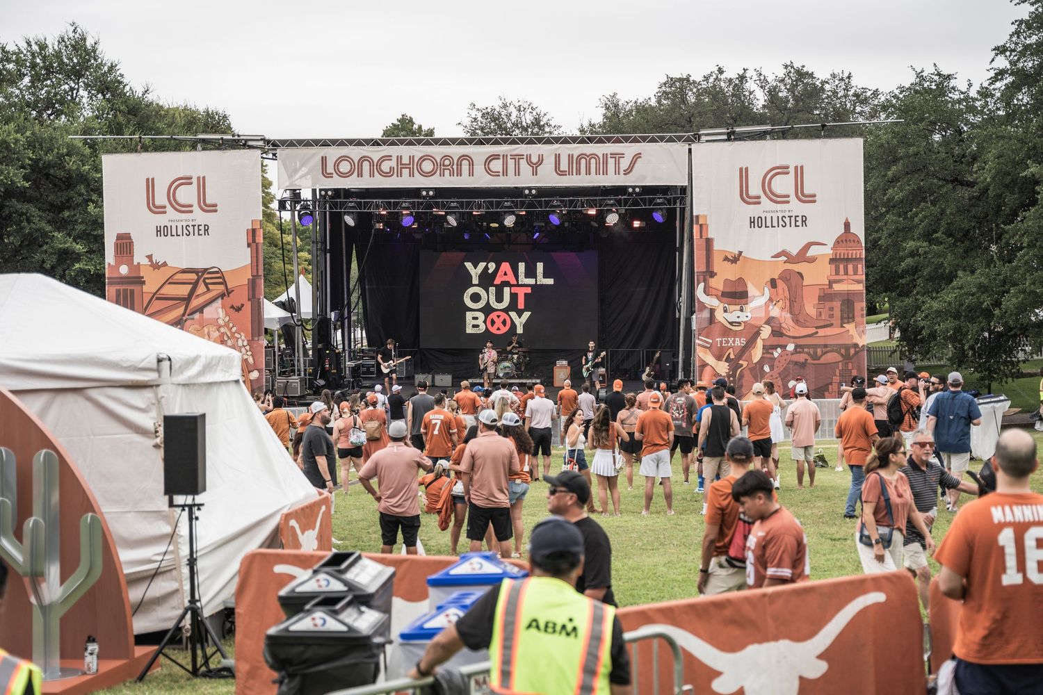 Outdoor music festival crowd gathered at Loughborough City Limits stage with orange banners and tents in background.