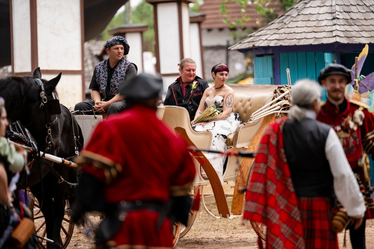 Performers in period costumes interact during a medieval renaissance fair with horses and traditional garments.