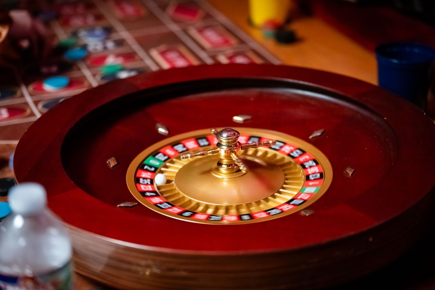 Close-up view of a casino roulette wheel with red and black numbers illuminated by warm lighting.