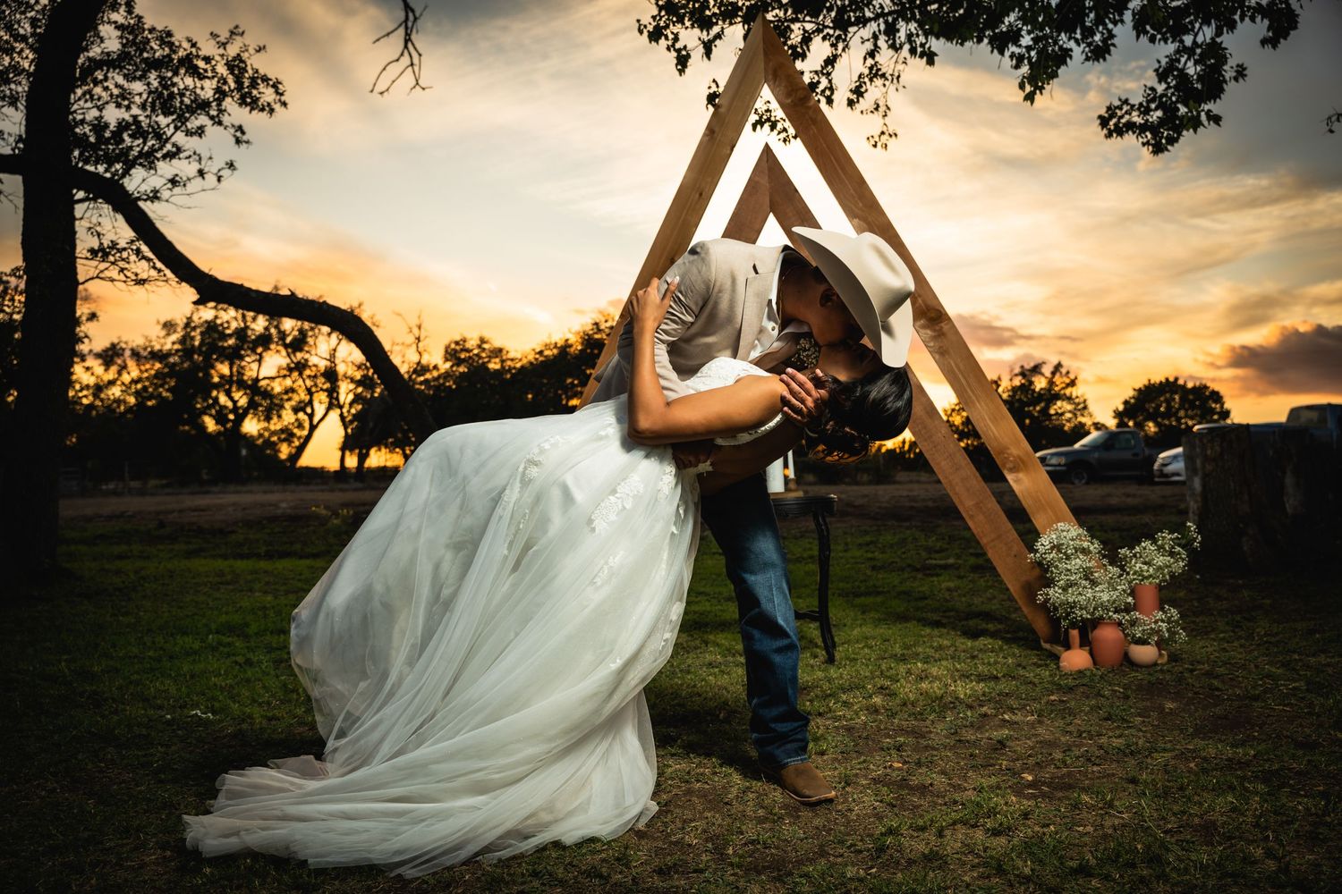 Romantic couple posing under a wooden triangle arch during golden hour.