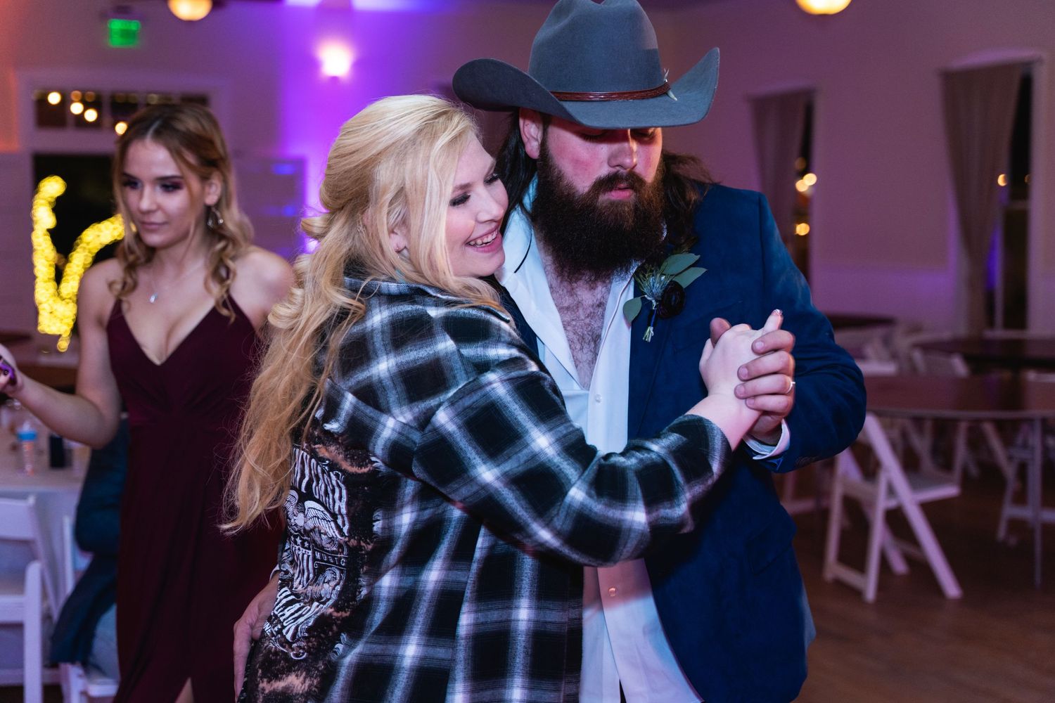 Couple dancing together at a western-themed wedding reception with plaid shirts.