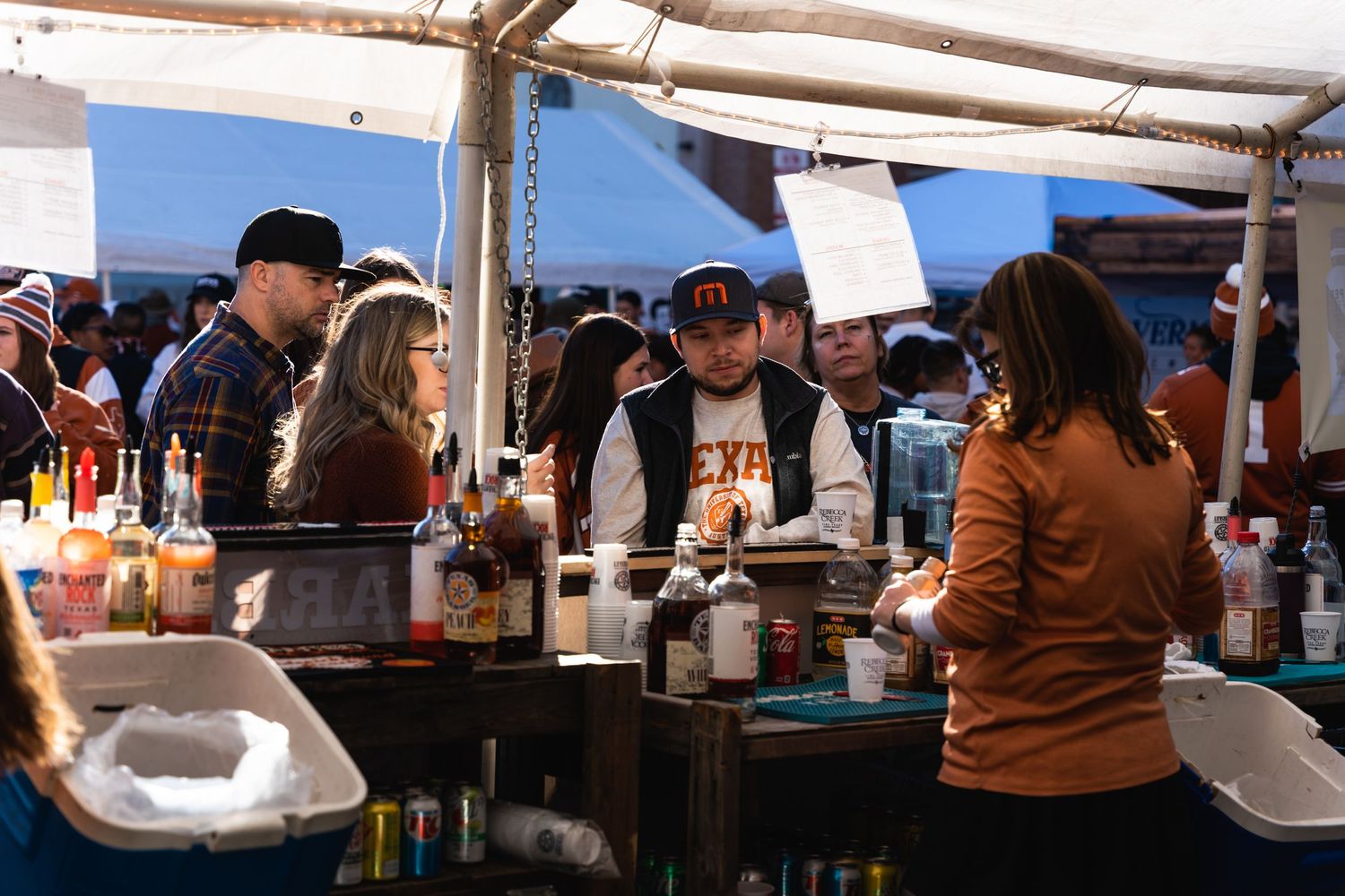 Bar service area under tent with people gathered around getting drinks.