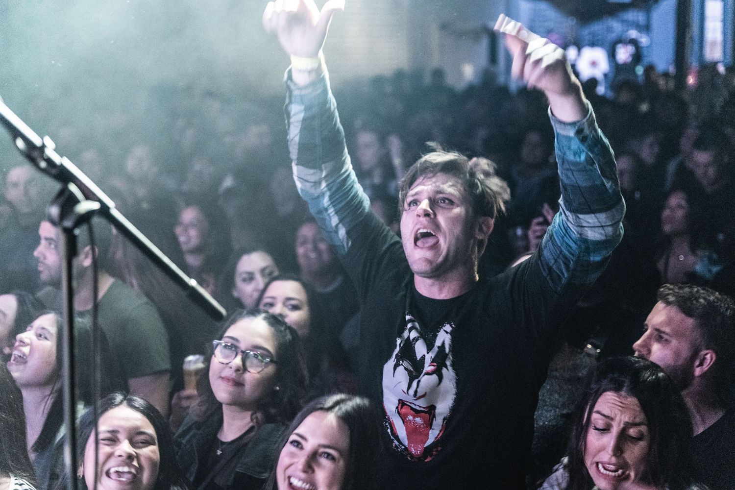 Concert attendees react passionately to live music in a dimly lit venue.