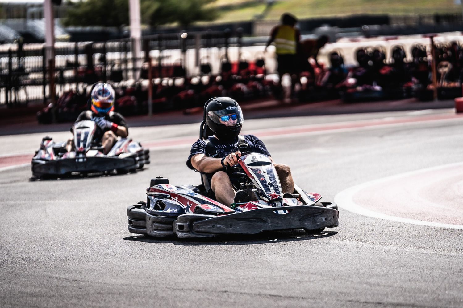 Two go-karts racing on an outdoor karting track during a competitive event.