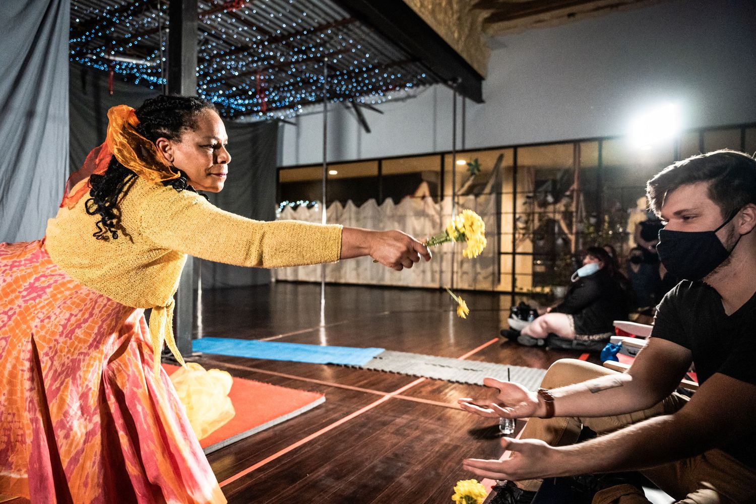 Performers interacting during theatrical production with dramatic lighting.
