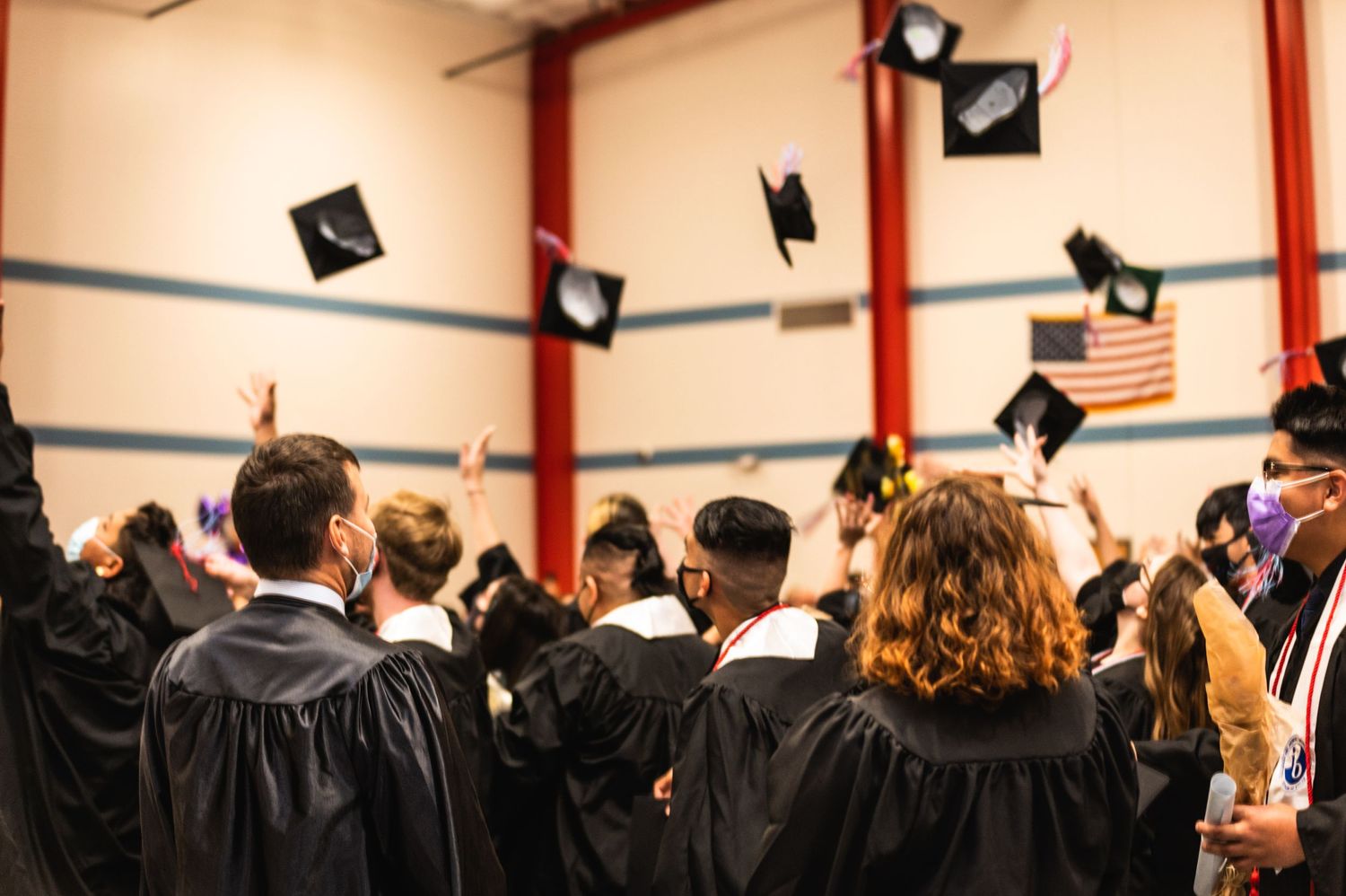 Graduates throwing mortarboard caps in air during graduation celebration.