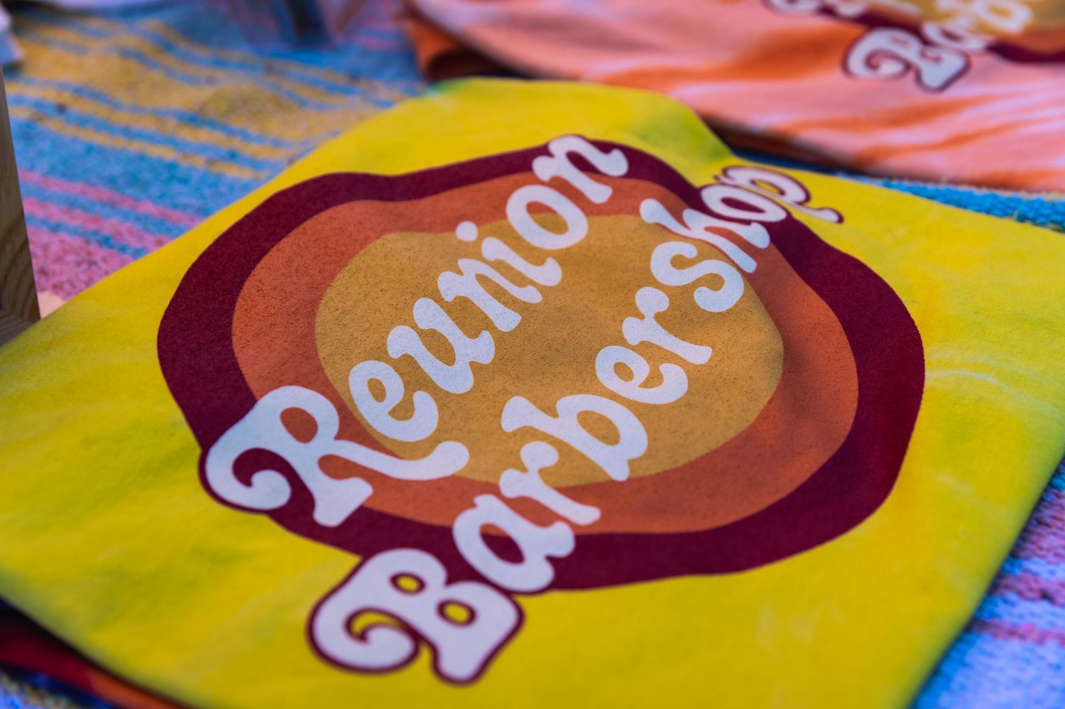 A yellow merchandise item with retro-style 'Reunion Barbershop' branding.