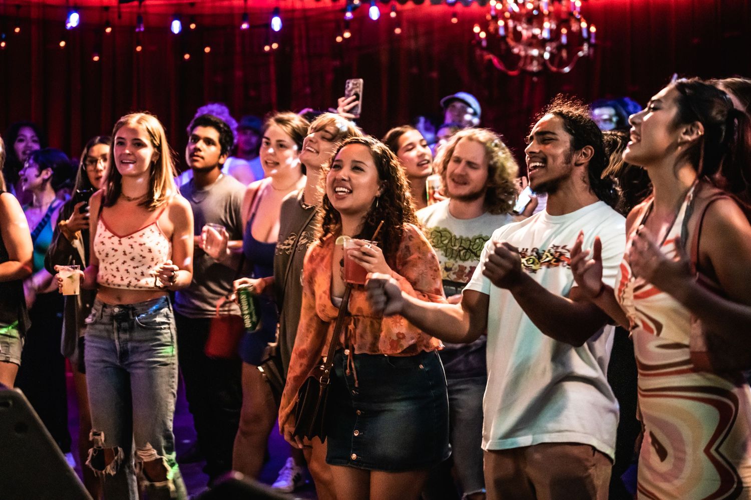 Energetic crowd enjoying live music performance under red stage lighting.