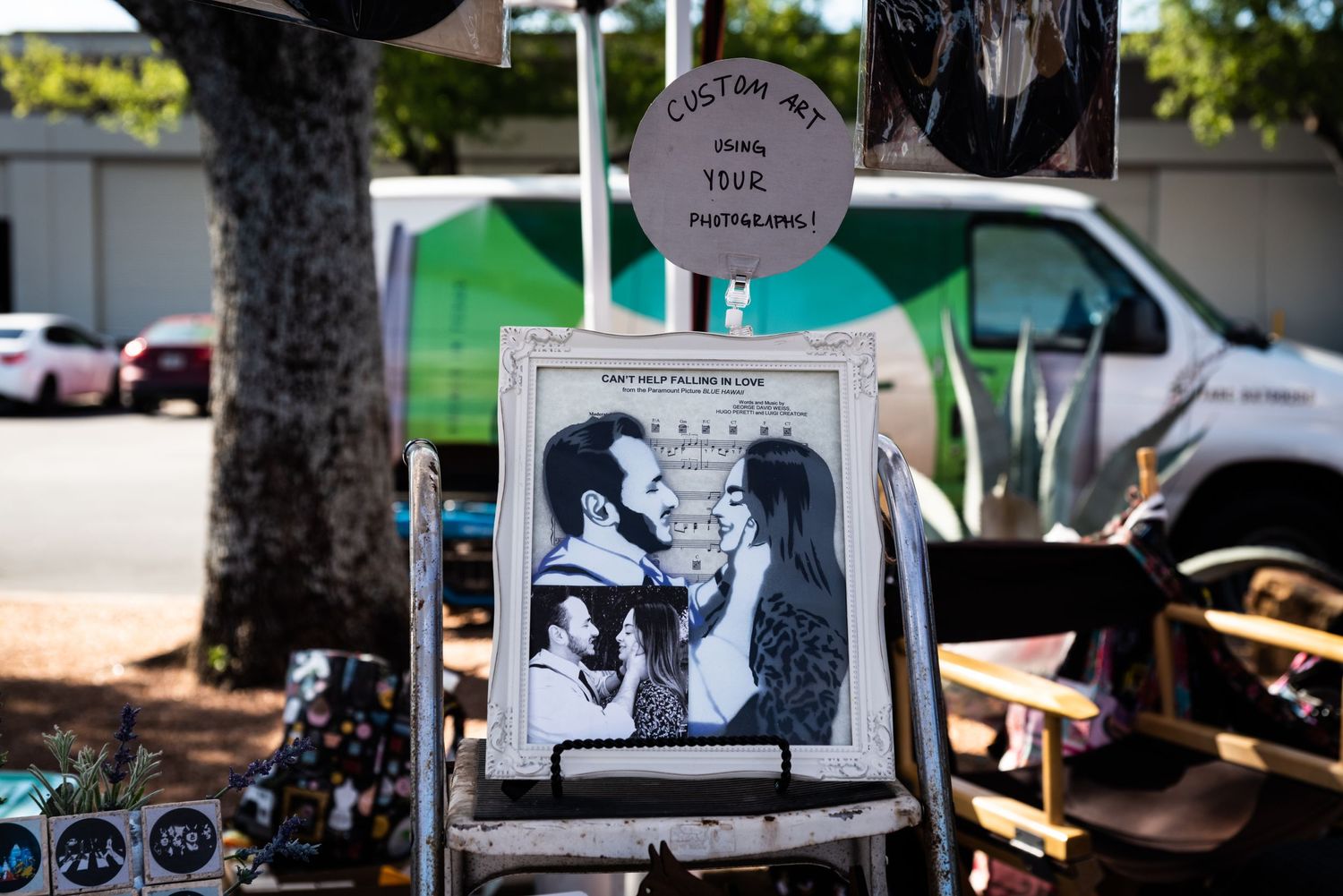 Framed black and white artwork displayed at an outdoor vendor market.