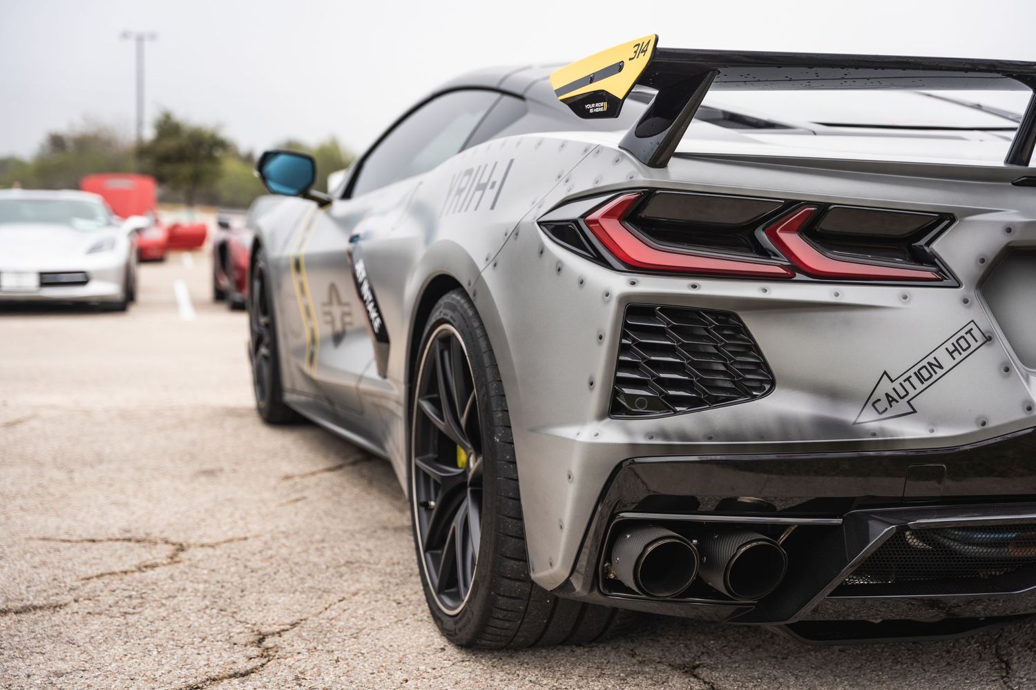 Rear view of a gray Chevrolet Corvette C8 showing modern taillights and aerodynamic details.