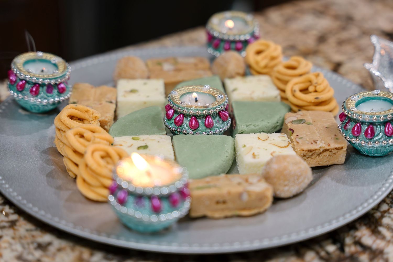 Decorative plate of assorted desserts and treats with ornate candle holders.