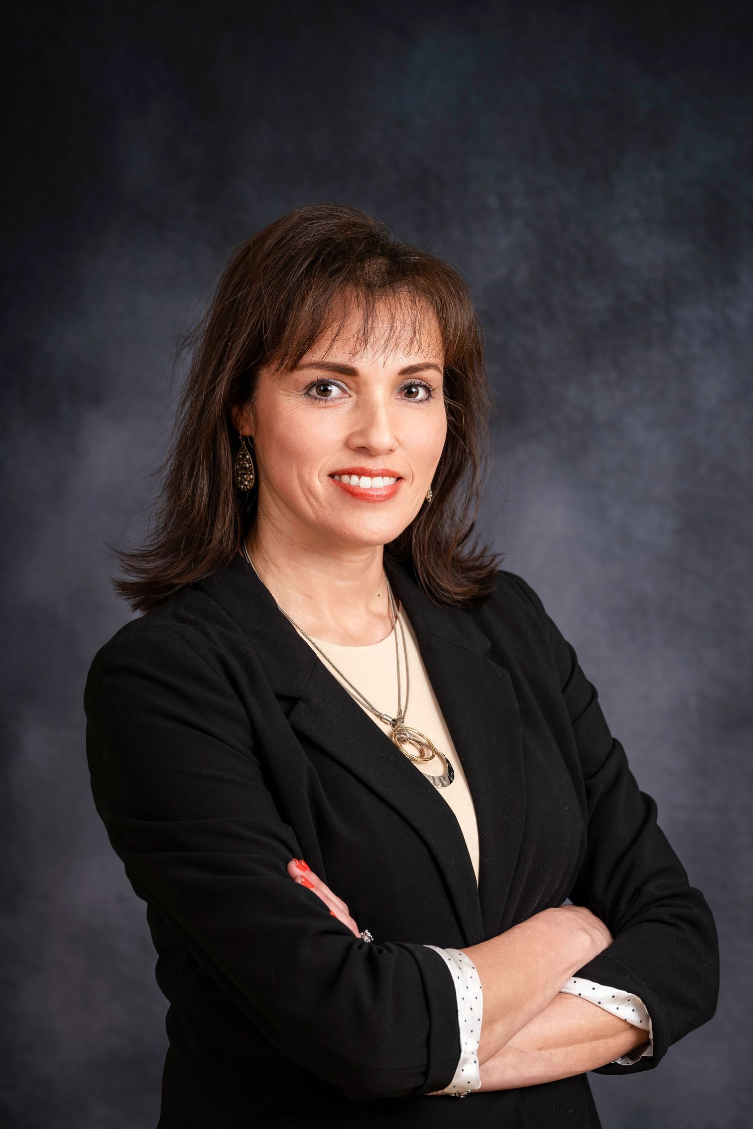 Professional portrait of a businesswoman in black jacket with arms crossed.