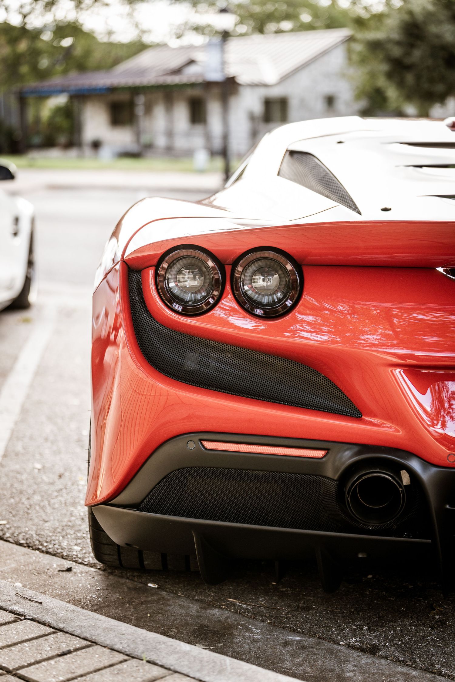 Close-up view of a red Ferrari's rear tail lights and carbon fiber detailing.