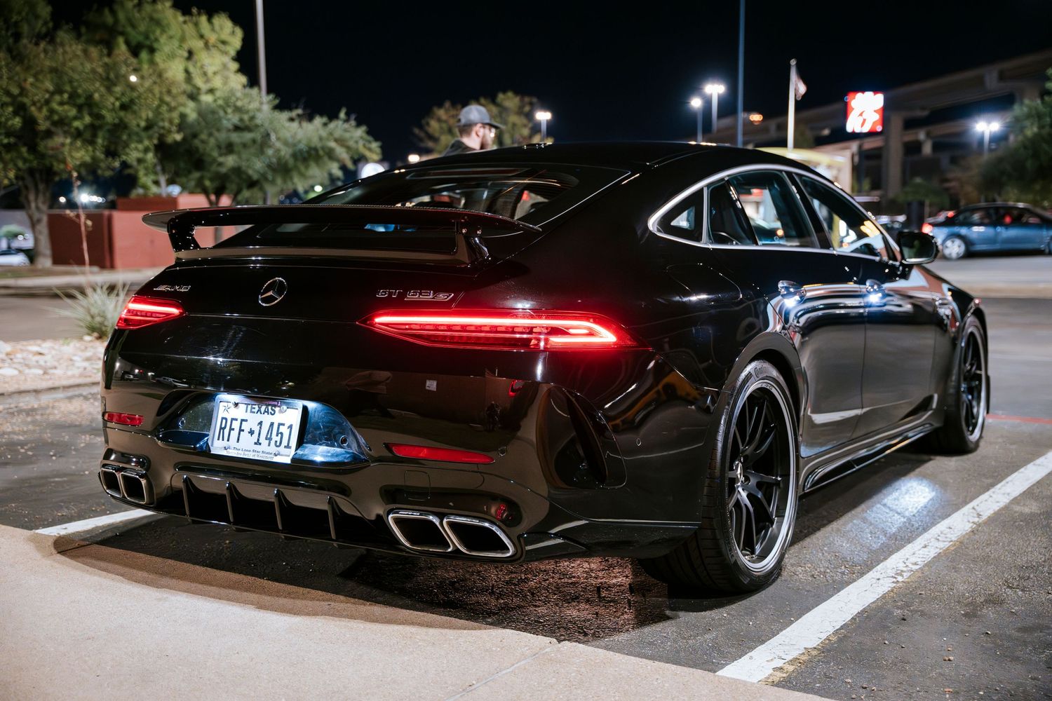 Black Mercedes-AMG GT 4-door coupe with distinctive red taillights and quad exhaust tips.