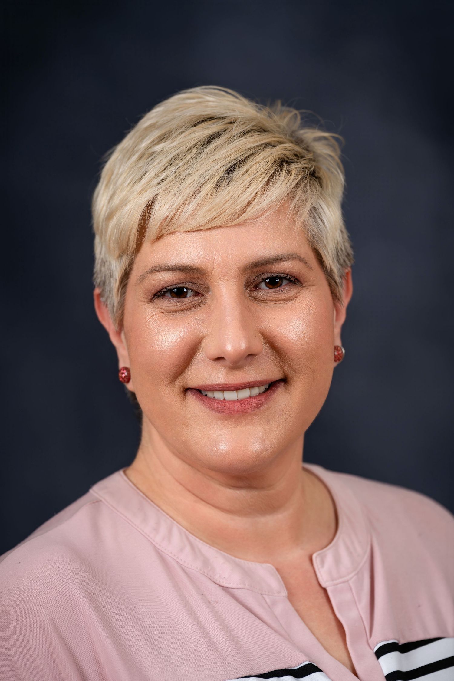 Close-up portrait of person with short blonde hair wearing pink and striped top.