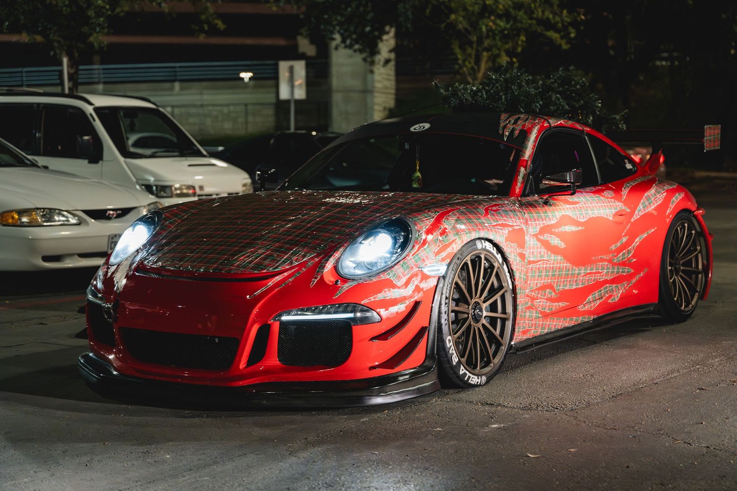 Modified red Porsche 911 GT3 with wide body kit and custom wheels parked at night.