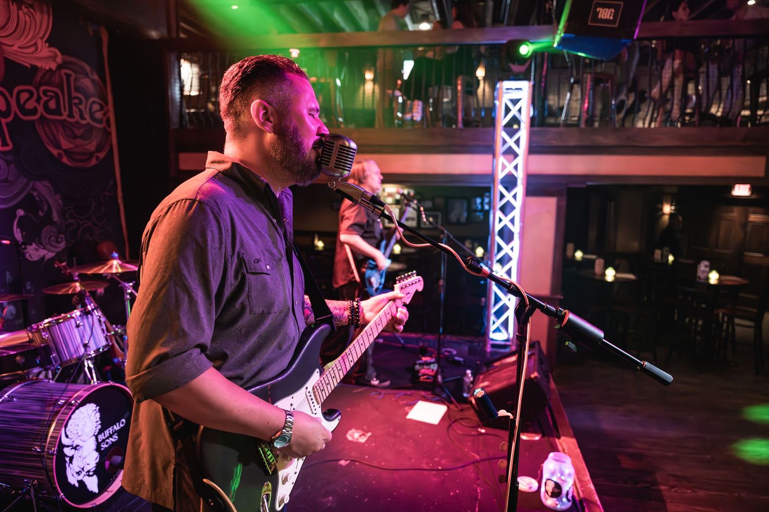 Musicians performing on stage with green and purple lighting effects in a club setting.