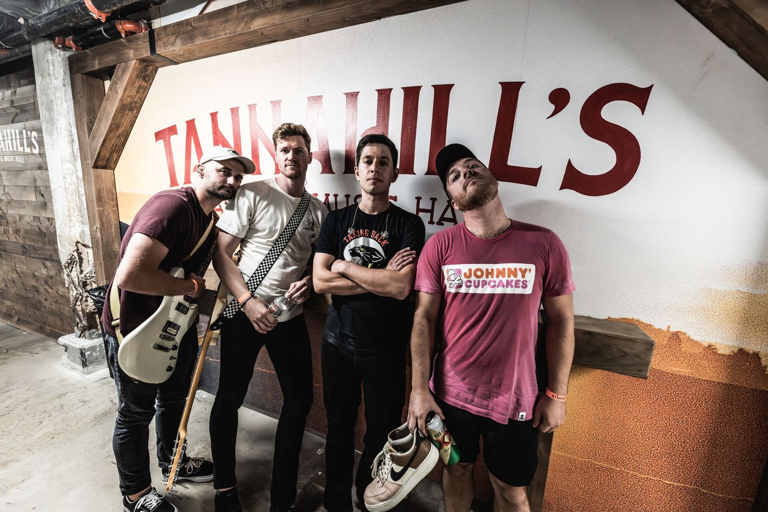 Band members pose together against wall with 'The Hill's' text in background.