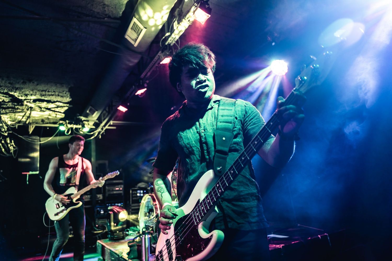 Musicians play guitars on stage with vibrant blue and white lighting effects.