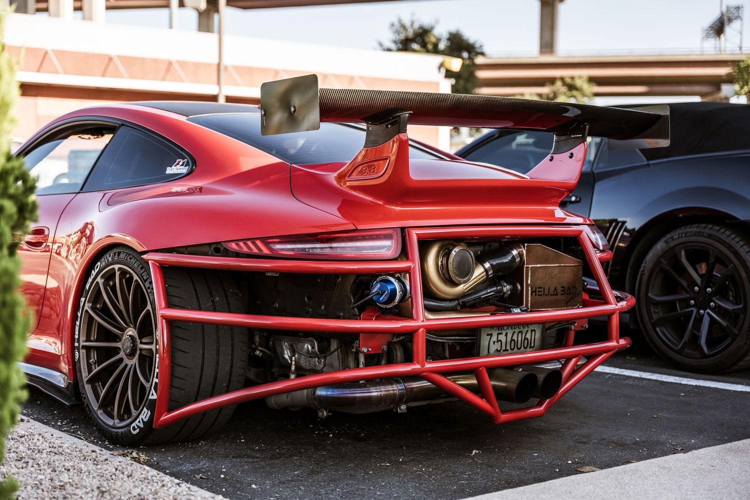 Rear view of a red sports car with aggressive aerodynamic modifications and black wheels.
