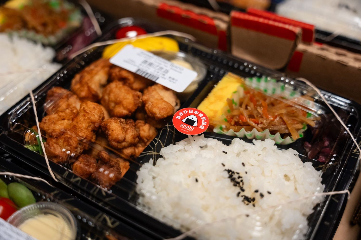 A Japanese bento box containing fried chicken, rice, and side dishes.