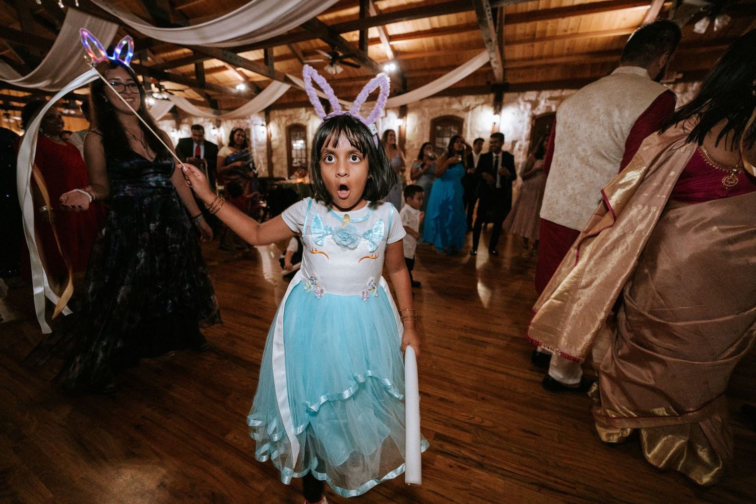 Young guest in a blue princess dress twirling on the dance floor at a celebration.