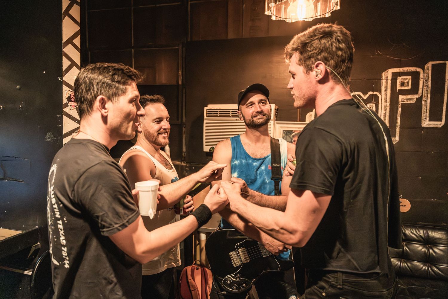 Musicians interact backstage at a concert venue during an intimate performance moment.