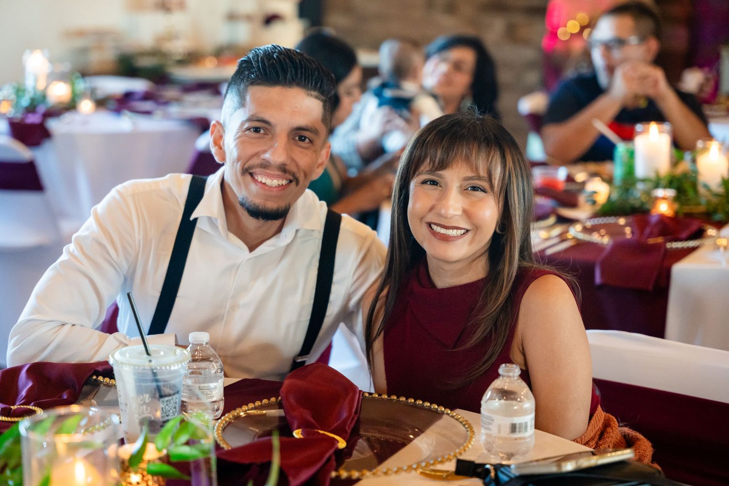 Wedding reception guests enjoying a meal at decorated tables with festive lighting.