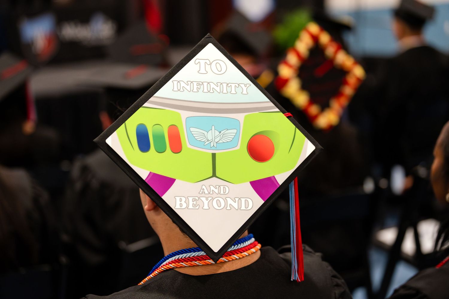 Graduation cap decorated with a Toy Story Buzz Lightyear inspired design featuring colorful elements.