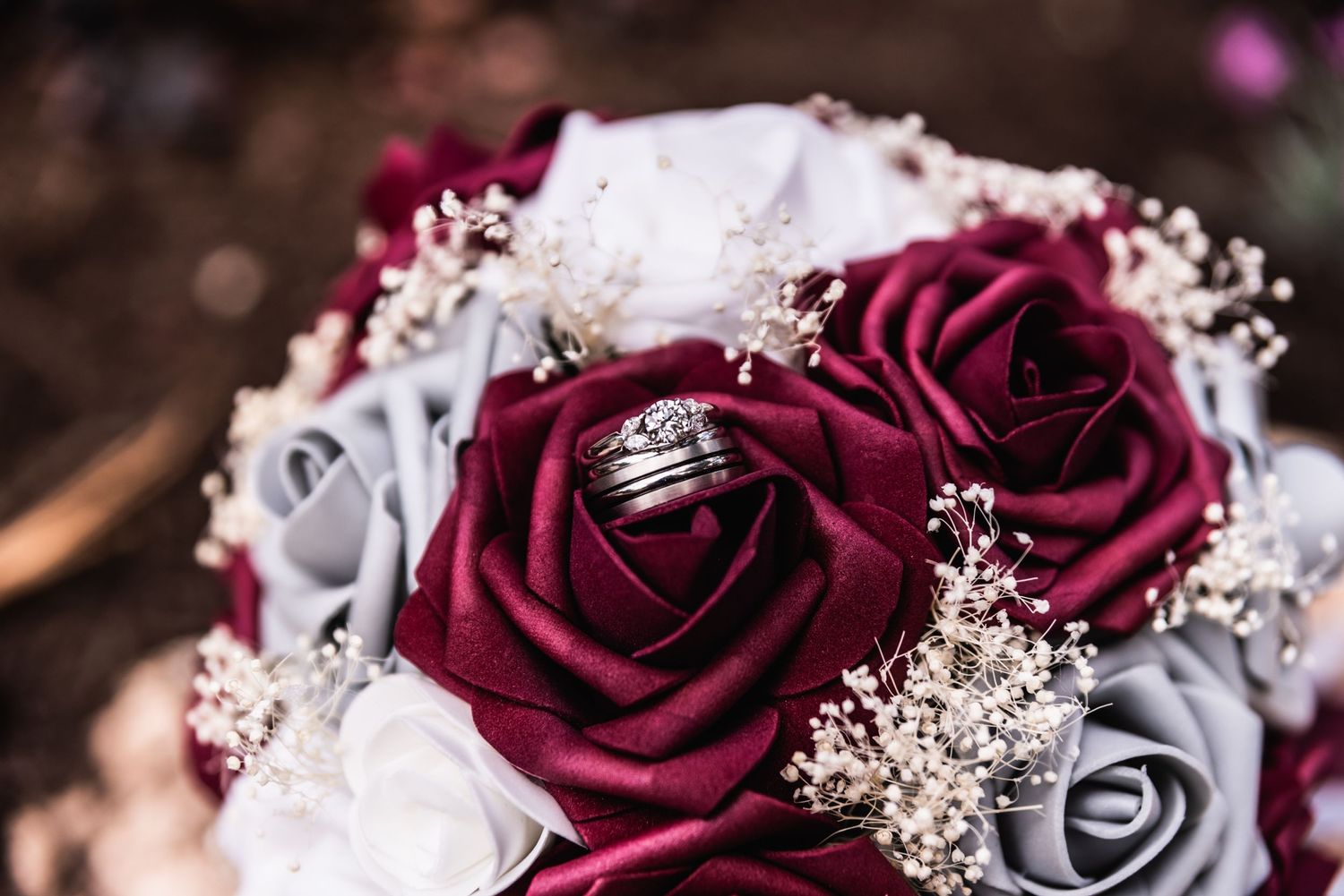 A stunning bouquet featuring deep burgundy and silver roses with delicate baby's breath accents.