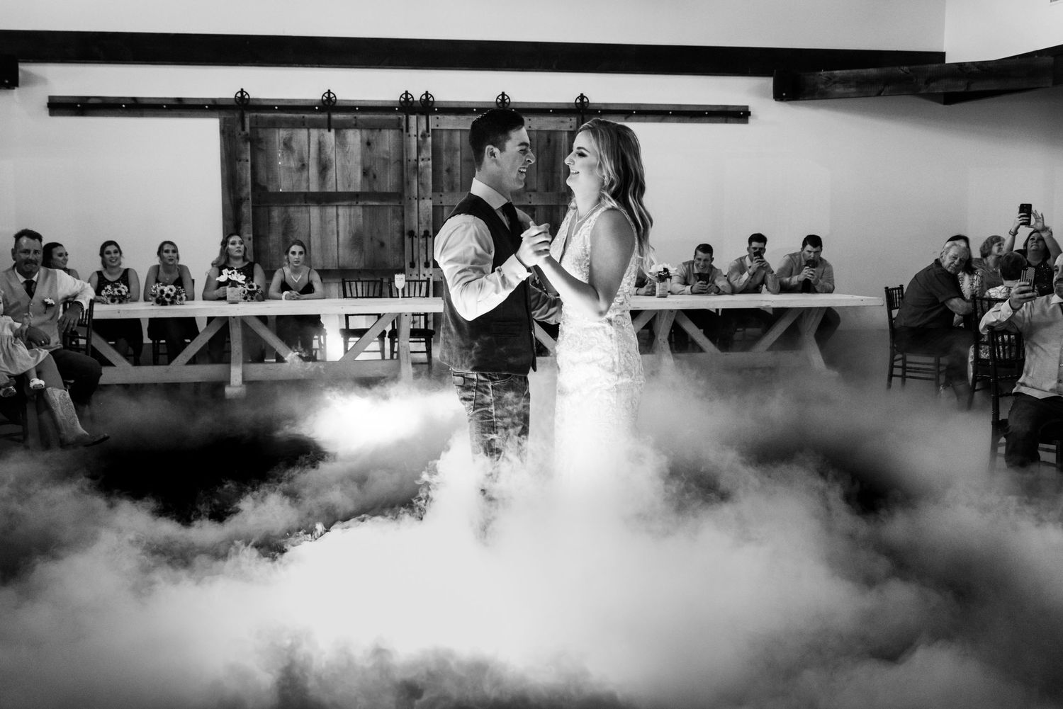 Black and white photo of a romantic first dance with dramatic fog effect on dance floor.